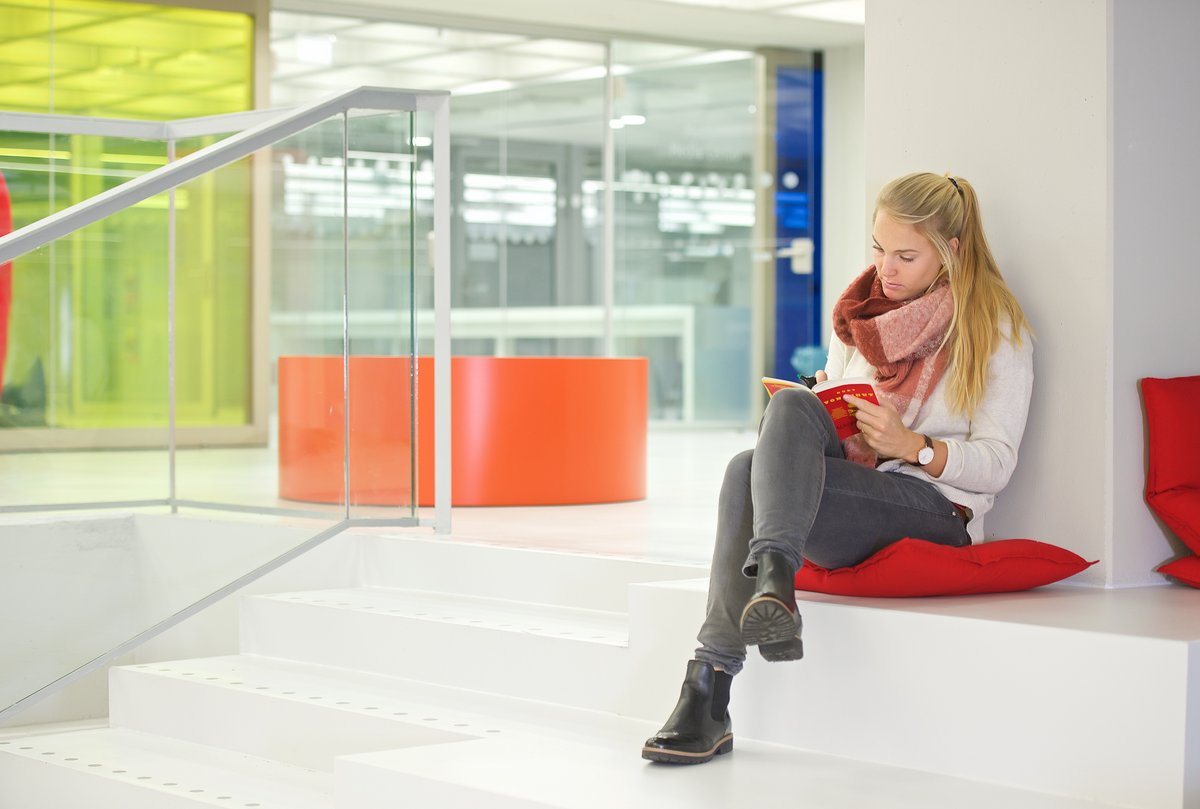Studentin liest auf den Sitzstufen der Bibliothek
